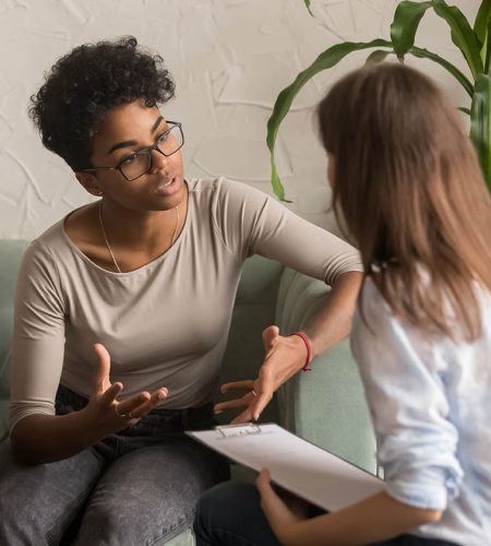 Unhappy jealous mixed-race wife talk to psychologist counselor complain on bad relationship with husband, african american family couple counseling have conversation about problem at therapy session